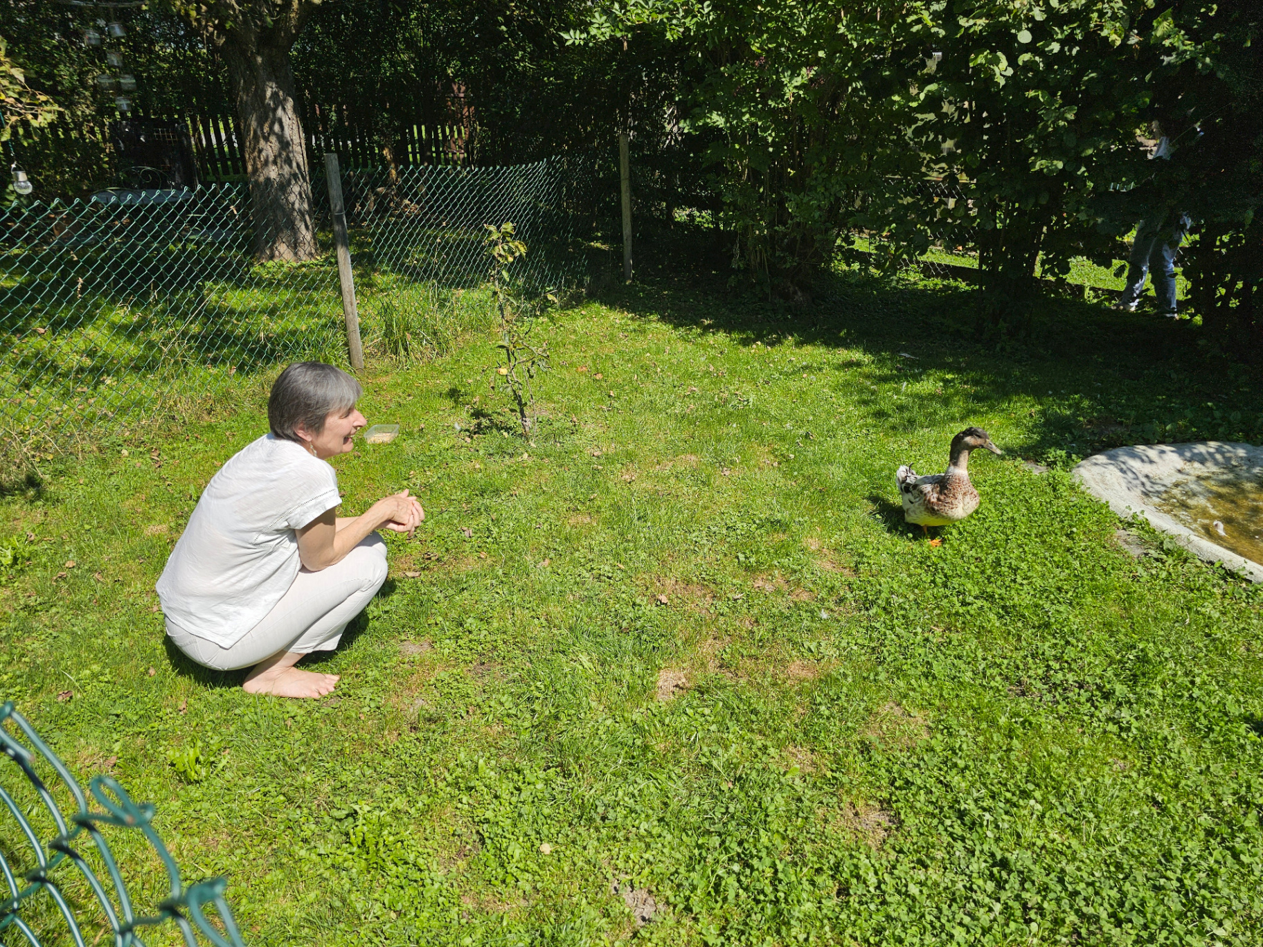 Andrea Beck hockt im Garten und beobachtet lächelnd eine Ente